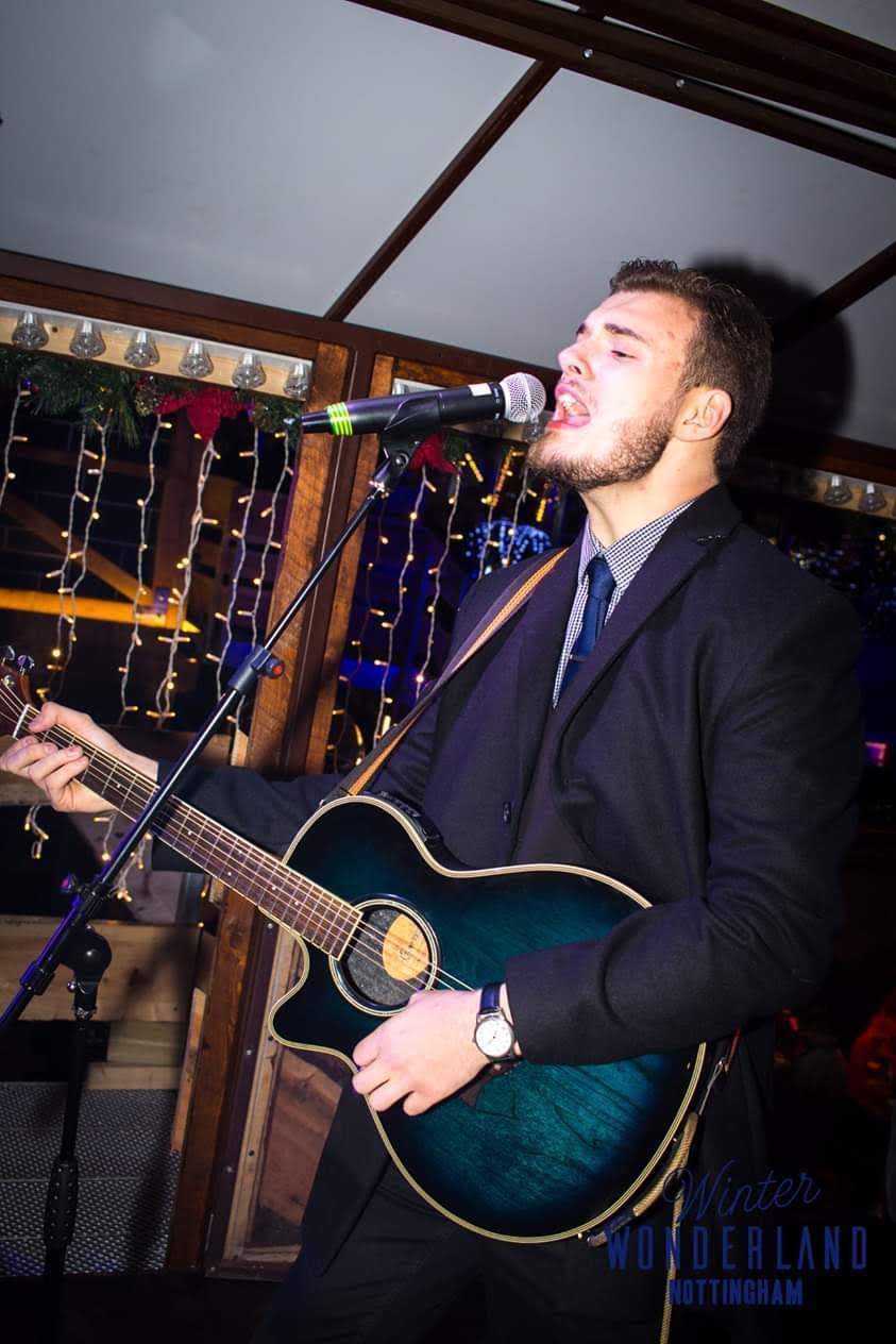 Acoustic Duo guitarist Jack Donald playing a blue guitar and singing through a microphone